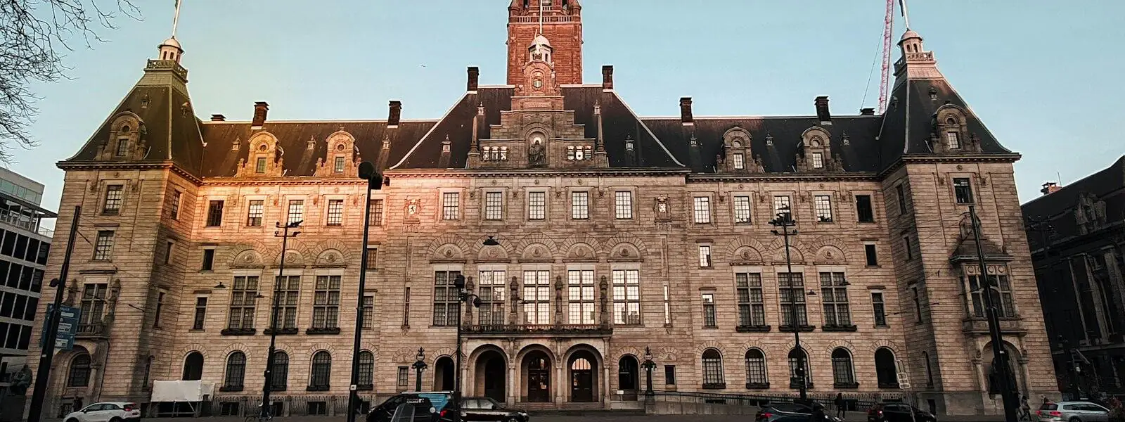 A Dutch city hall in brick and stone with a central clock tower, in early evening light